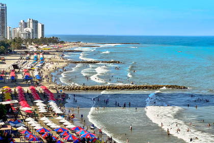 Zatłoczona plaża miejska widziana z góry. W tle wysokie budynki.