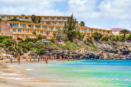 Plaża z turkusową wodą. W tle budynek hotelu.