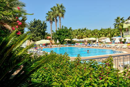 Basen z palmami, leżakami i parasolami w hotelu.