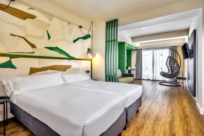 Pokój hotelowy z dwoma łóżkami, wiszącym fotelem i ścianą ozdobioną abstrakcyjnym wzorem.