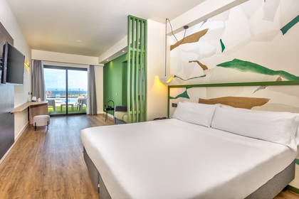 Pokój hotelowy z balkonem i widokiem na morze. W pokoju znajduje się łóżko.