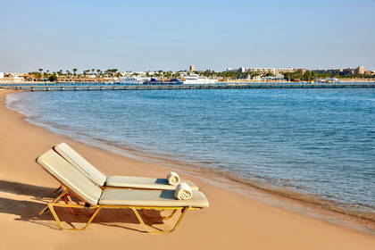 Dwa leżaki z ręcznikami na piaszczystej plaży.