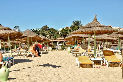 Plaża z parasolami i leżakami.