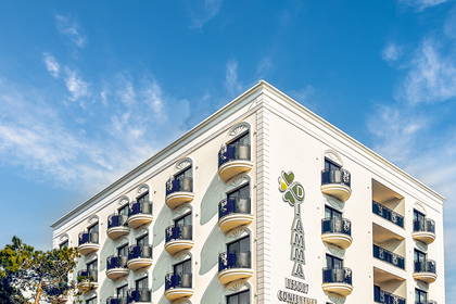 Budynek hotelu z balkonami widziany z dołu na tle błękitnego nieba.
