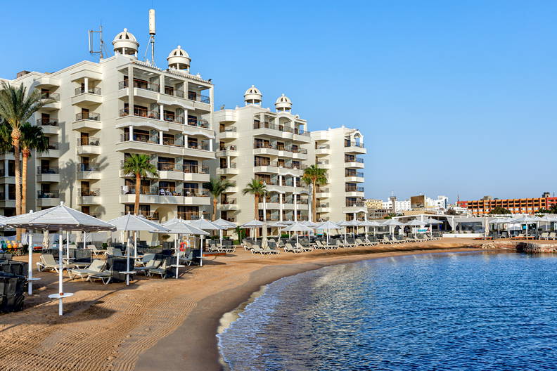 Plaża z leżakami i parasolami przed hotelem.