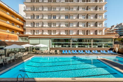 Hotel z basenem, leżakami i balkonami w pokojach.