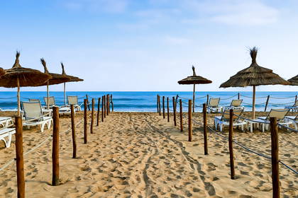 Plaża z parasolami, leżakami i drewnianymi konstrukcjami.