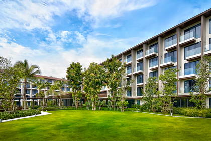 Hotel z trawnikiem i drzewami.