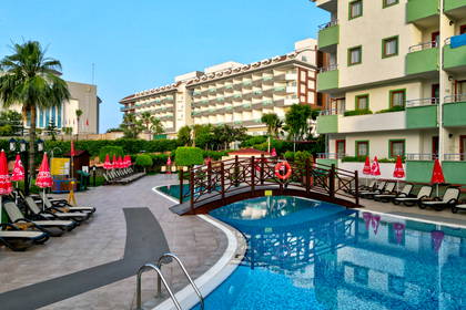 Basen w hotelu z drewnianym mostkiem i leżakami.