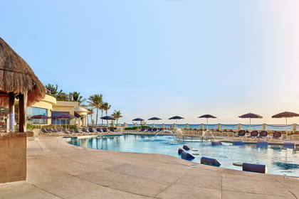 Basen w kurorcie z barem pod strzechą i leżakami do opalania.
