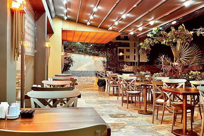 Pusta restauracja na zewnątrz z drewnianymi stołami i krzesłami.