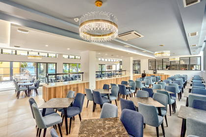 Restauracja z niebieskimi krzesłami i dużymi żyrandolami.