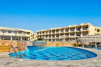 Basen hotelowy na tle zabudowań.