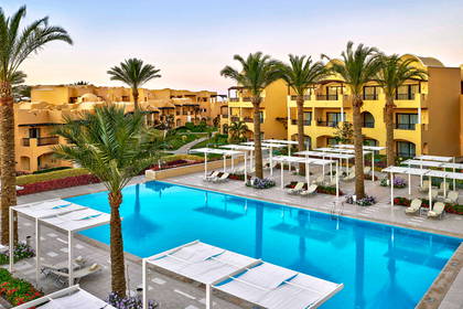 Kompleks hotelowy z basenem, palmami i leżakami do opalania.