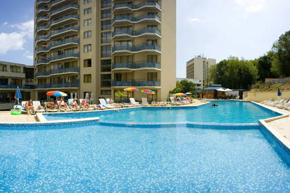 Hotel z basenem. Osoby wypoczywają na leżakach.