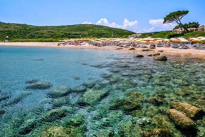 Plaża z leżakami i parasolami widziana od strony morza.