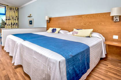 Pokój hotelowy z łóżkiem małżeńskim i niebieskim akcentem dekoracyjnym.