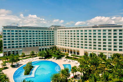 Hotel z basenem otoczonym palmami, widok z góry.
