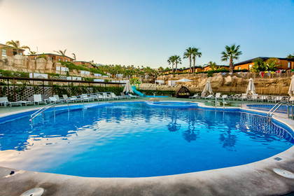 Kompleks hotelowy z basenem i palmami.