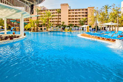 Hotelowy basen z leżakami. W tle palmy.