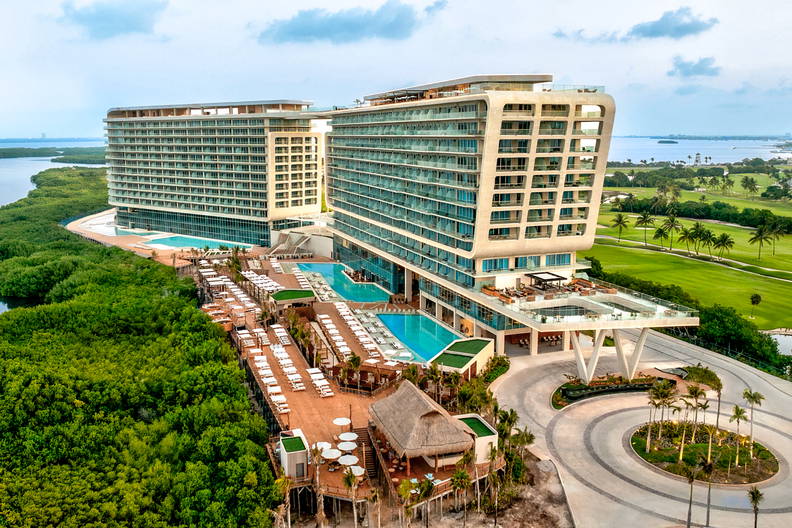 Widok z góry na luksusowy kurort z basenami, palmami i polem golfowym.