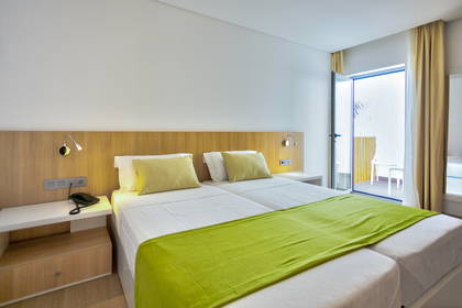 Pokój hotelowy z dwoma pojedynczymi łóżkami i balkonem.