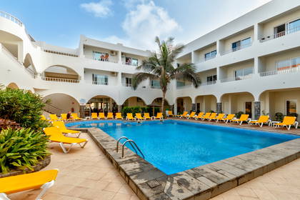 Dziedziniec hotelowy z basenem i leżakami do opalania.