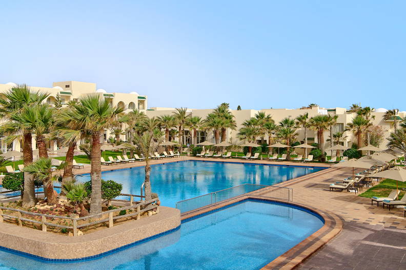 Kompleks basenowy w hotelu z palmami i leżakami do opalania.