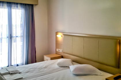 Pokój hotelowy z łóżkiem i oknem zasłoniętym zasłonami.