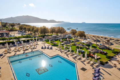 Hotel z basenem i plażą widziany z góry, z morzem w tle.