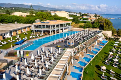 Widok z góry na luksusowy hotel z basenami, leżakami i widokiem na morze.
