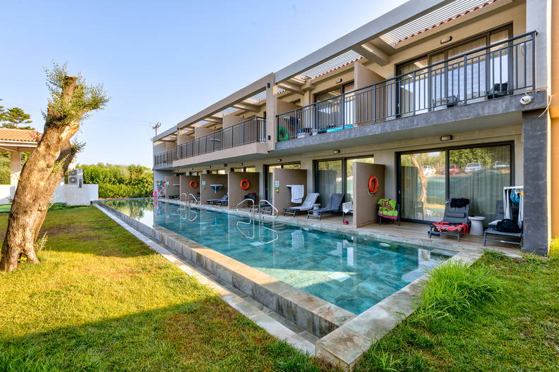 Dwupiętrowy budynek z balkonami nad basenem.