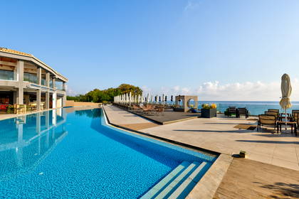 Basen, leżaki i morze w słonecznym kurorcie.