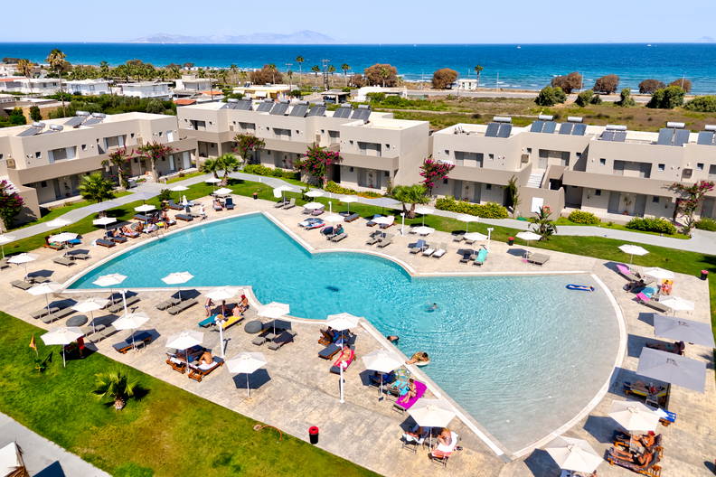 Kompleks hotelowy z basenem i leżakami do opalania.