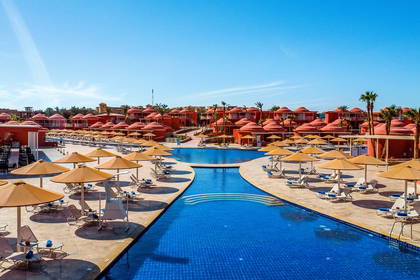 Kompleks hotelowy z basenem, leżakami i parasolami.