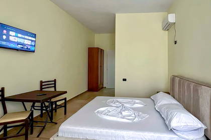 Jasny pokój hotelowy z łóżkiem, telewizorem i szafą.