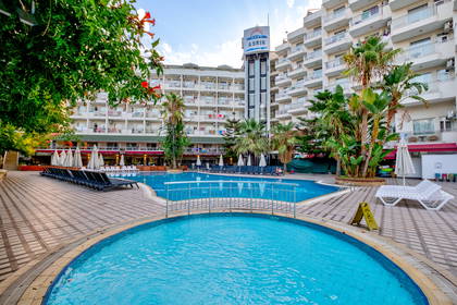 Kompleks hotelowy z basenem i leżakami do opalania.