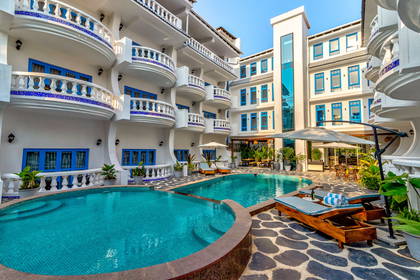 Hotel w stylu śródziemnomorskim z basenem, leżakami i balkonami.