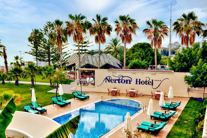 Basen hotelowy z leżakami otoczony palmami.