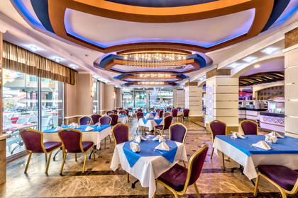 Restauracja z elegancko nakrytymi stołami i ozdobnym sufitem.