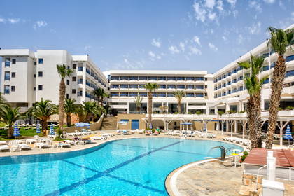 Hotel z basenem, leżakami i palmami.