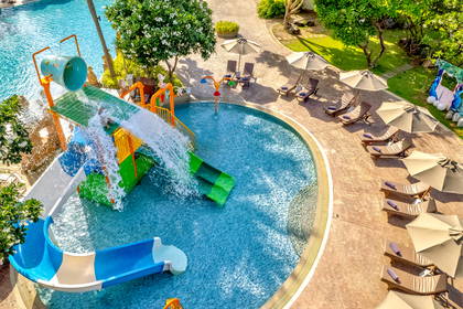 Widok z góry na hotelowy park wodny z kolorową zjeżdżalnią i basenem dla dzieci.