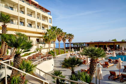Nowoczesny hotel z basenem, palmami i widokiem na morze.