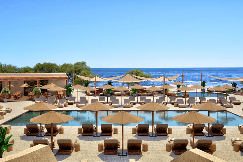 Widok z góry na basen z leżakami i parasolami w nadmorskim kurorcie.