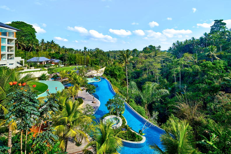 Hotelowy basen bez krawędzi (tzw. infinity pool) otoczony tropikalną roślinnością, widok z góry.