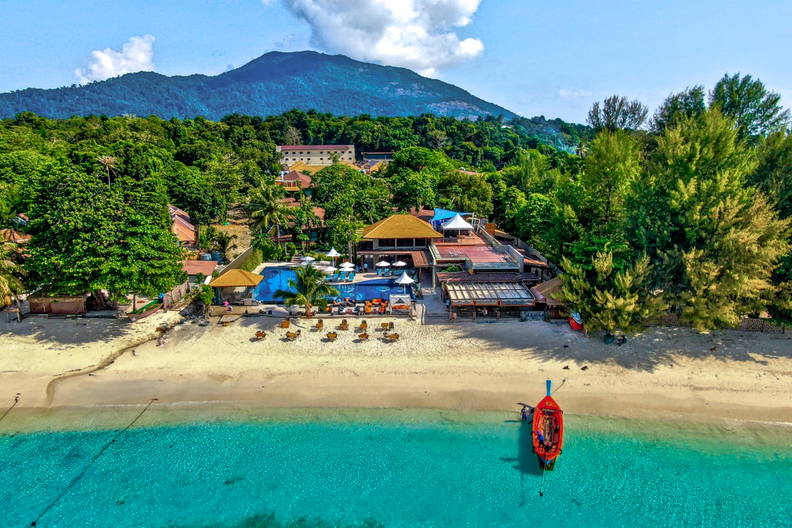 Plaża z czerwonym statkiem widziana z góry.