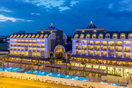 Oświetlony nocą hotel z basenami.