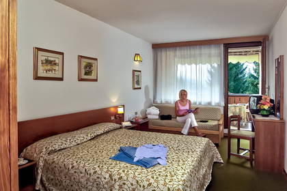 Kobieta czyta gazetę siedząc na kanapie w pokoju hotelowym.