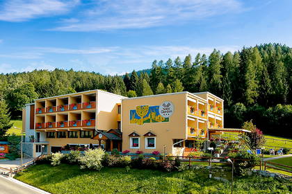 Hotel Garden z balkonami na tle lasu.
