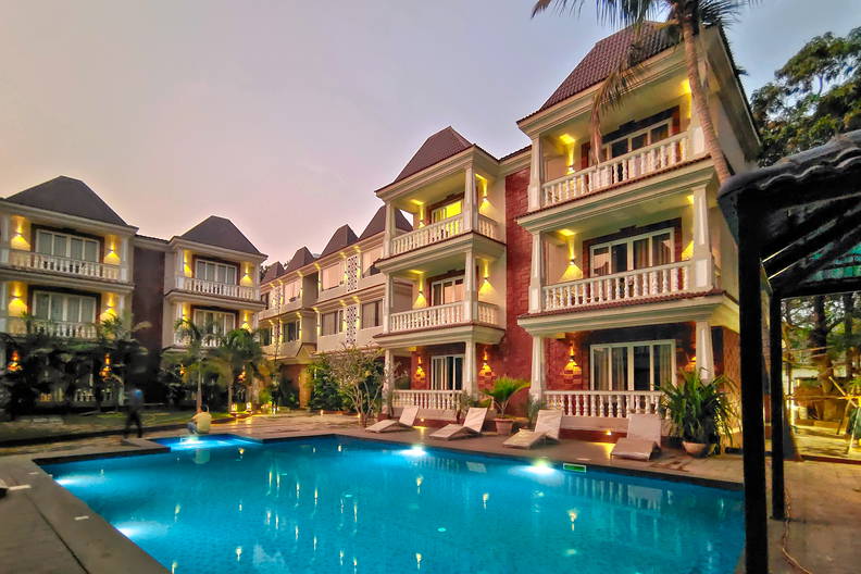 Kompleks hotelowy z basenem oświetlonym po zmroku.